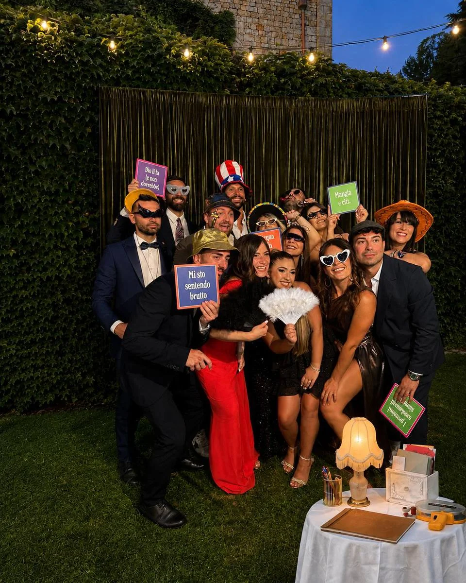 Gruppo ospiti con gadget e cartelli al PhotoBooth in serata
